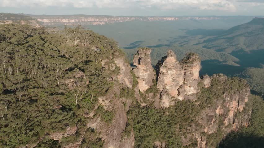 Breathtaking drone footage of the iconic Three Sisters rock formation in the Blue Mountains, NSW, showcasing dramatic cliffs, lush valleys, and serene natural beauty from above.