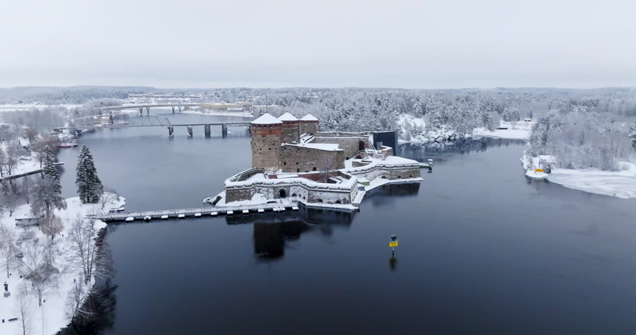 Drone approaching the snowy Olavinlinna castle, gloomy, winter day in Finland