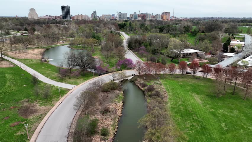 Drone view of St Louis, Missouri skyline from vibrant forest park on a cloudy day in a midwest city