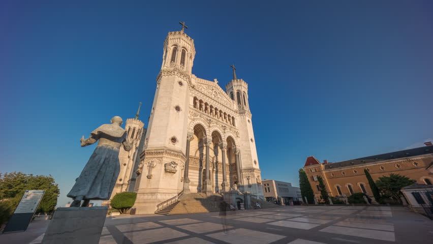 Hyperlapse front view of the Basilica of Notre Dame de Fourviere during sunset in Lyon, France. This iconic minor basilica is illuminated with warm light, overlooking the city from a hilltop timelapse