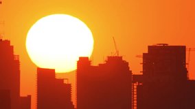 Big yellow and red sunset twilight timelapse with orange and red sky in urban cityscape with silhouette of the buildings. Beautiful dramatic and clear big disk sun set behind skyscrapers time lapse - Powered by Shutterstock - Get 15% off with code: PIKWIZARD15