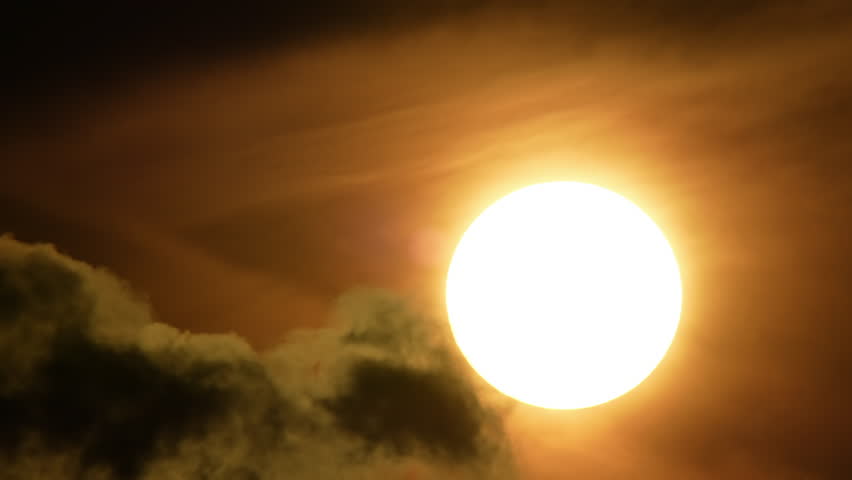 Apocalyptic cinematic big sun disk sun set behind dark dirty clouds timelapse. Dazzling hot sunset sun blasting through dark Armageddon clouds time lapse. Judgment day mood and atmosphere.