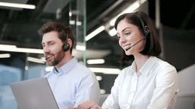 Customer service representatives working at desks with headsets in modern office. A team of call center agents, men and women helping online, speak on a video call using a laptop focusing on client - Powered by Shutterstock - Get 15% off with code: PIKWIZARD15