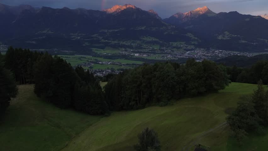 Aerial view of Sunrise behind Mountain Range in Austria with Rainbow in Background