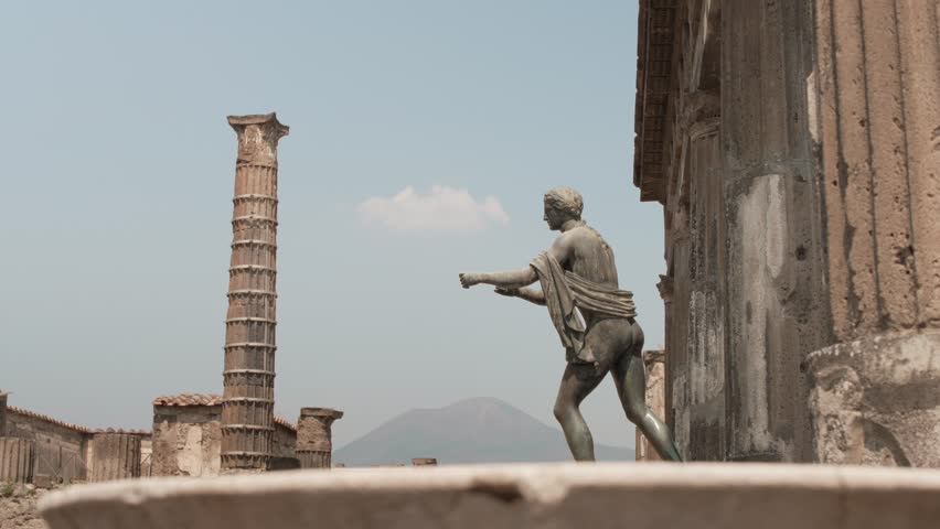 Mount Vesuvius looms in the background amidst the ruins and remaining statues of Pompeii.