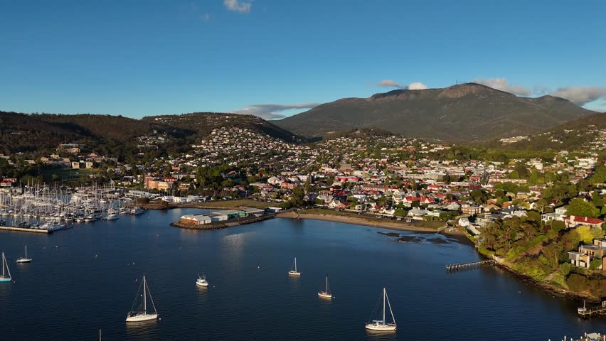 Panoramic shot of the harbor of Hobart city during sunset, aerial shot orbital
