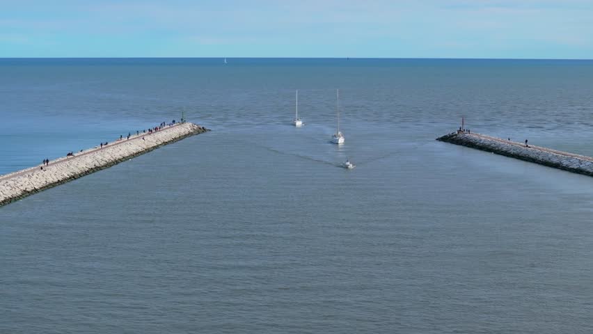 aerial view of sailing yachts coming into the breakwater inlet Livenza, in Caorle, Italy