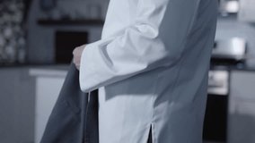 A static side shot captures a white male chef putting on his apron and preparing to work in the kitchen. This video highlights the importance of kitchen readiness and professional attire. - Powered by Shutterstock - Get 15% off with code: PIKWIZARD15