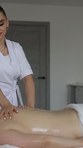 Vertical video woman is providing a relaxing massage to a man at a spa