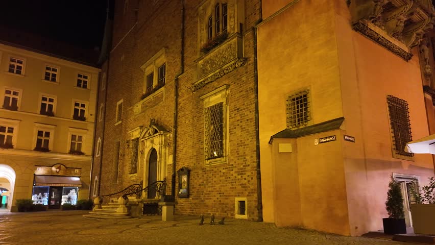 Illuminated night view of the historic Wroclaw Old Town Hall located in the vibrant market square, showcasing exquisite architectural details and atmospheric lighting.