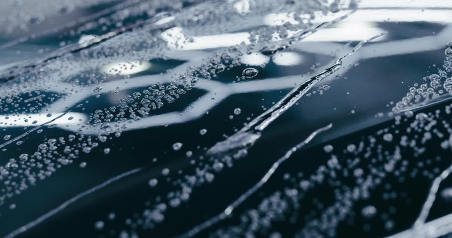 Witness the ultimate in paint protection as water beads up and runs off a car's surface. This close-up shot demonstrates the effectiveness of a high-quality wax or sealant.