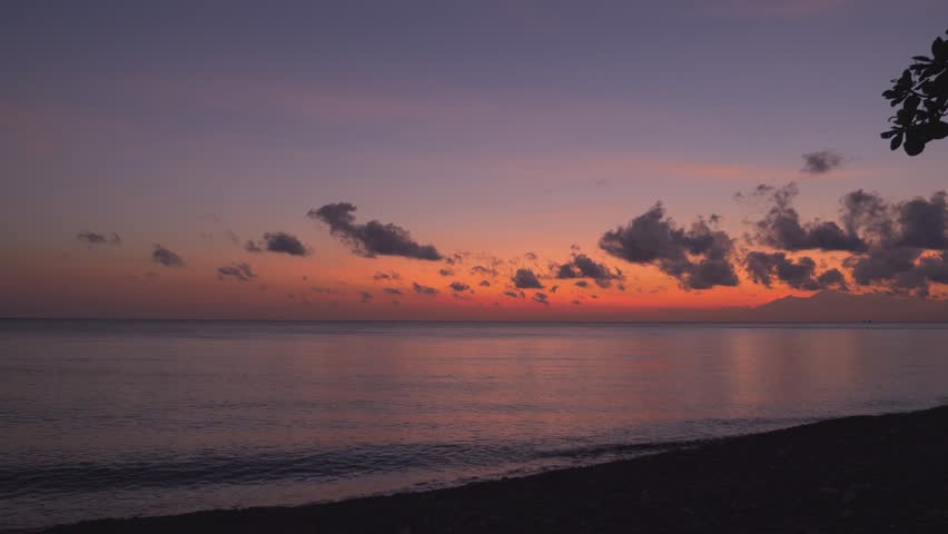 On sea shore looking at calm sea and red sky before sunrise. Location: Amed Bali Indonesia