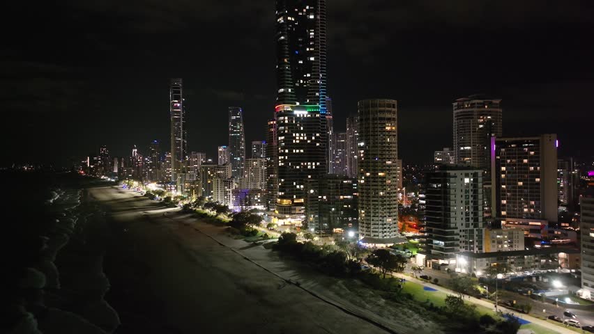 Aerial crane of skyscraper tower building in Gold Coast, Australia illuminated at night.