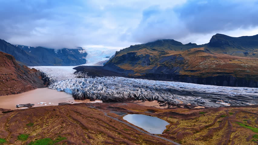 Iceberg ranges among the mighty mountains. Heavy cloudscape covering the mountain tops. Unreal landscape of Iceland.