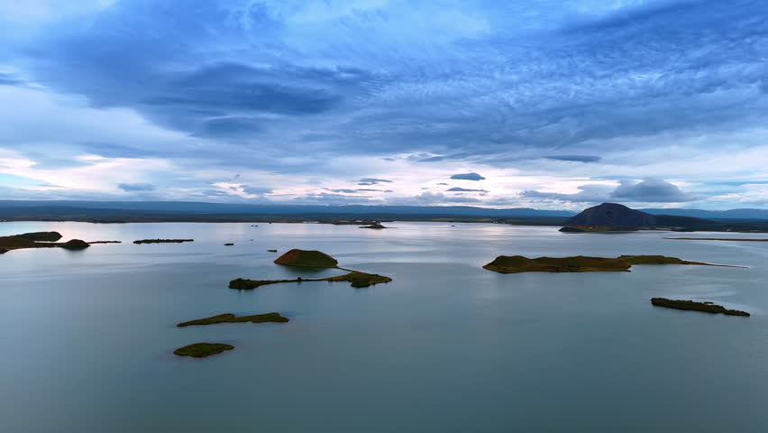 Waterscape with peaceful surface and little rock islands sticking out of water. Dramatic cloudscape covering the sky. Scenic view of Iceland.