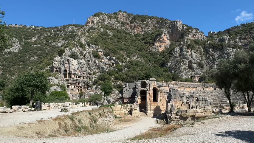 The ruins of the Roman amphitheater and the Lycian rock tombs at the Myra Ancient City on a sunny day in Demre, Antalya, Turkey