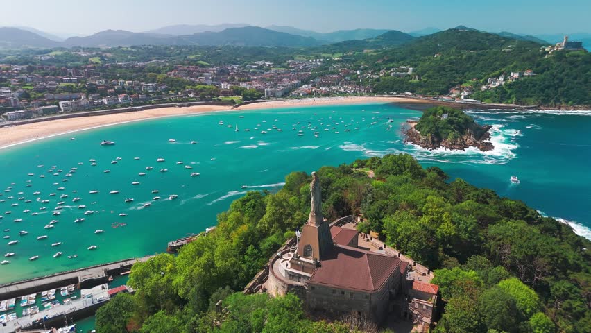 Aerial view of the beautiful coast of San Sebastian town, Basque country, Spain. Flying over the statue of Christ stands watch over magnificent Bay of Biscay, Donostia. Orbit shot