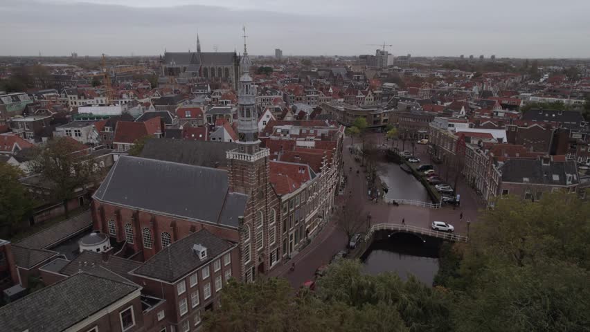 A drone footage of St. Louis Catholic Church (Heilige Lodewijkkerk) and the riverfront buildings on an overcast day in Leiden, Netherlands