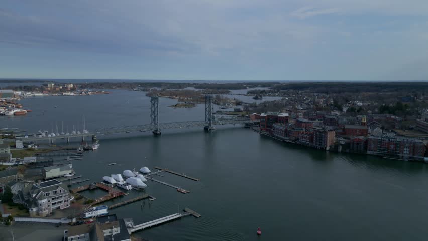 Aerial establishing overview of Portsmouth harbor and memorial bridge featuring docks, anchored boats, and calm waters