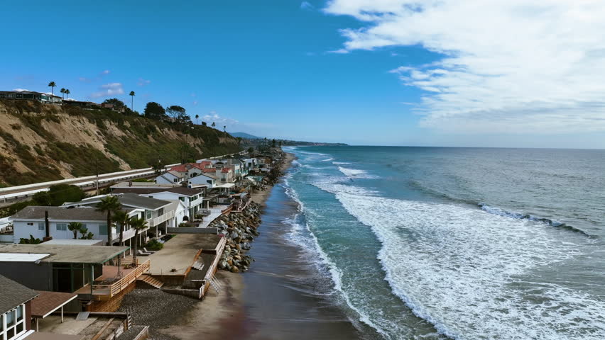 Aerial view passing waves and homes, along the coastline of San Clemente, CA, USA