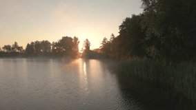 The sun rises over a misty lake surrounded by trees and fields - Powered by Shutterstock - Get 15% off with code: PIKWIZARD15