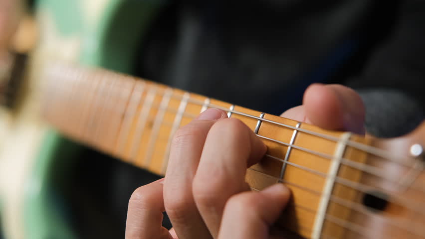 Close-up of gifted male musician playing electric guitar, immersed in songwriting and improvisation