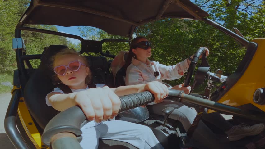 Mom and daughter ride a buggy, a girl with her mom on a buggy, ride a buggy in the mountains