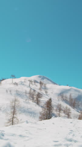 SLOW MOTION CLOSE UP: Extreme snowboarder jumping in big mountain ski resort. Detail of snowboard taking off the kicker in groomed snow park. Snowboarding jump on sunny winter day in snb park