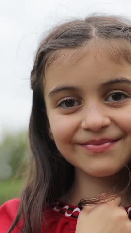 Vertical video a beautiful little girl with dark hair in a red dress