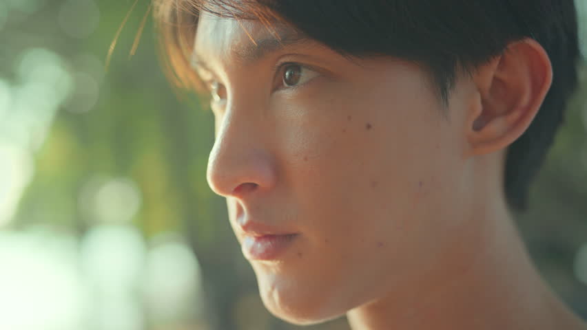 Closeup of face asian male opening eyes looking straight while thinking of goal for exercise before running in public park