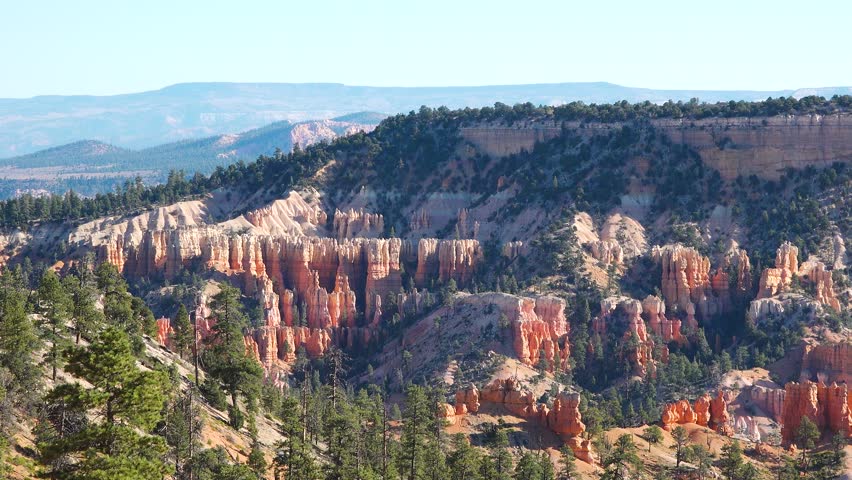 Discover the breathtaking landscapes of Bryce Canyon featuring dramatic red rock formations, towering cliffs, and vast vistas under a clear blue sky.