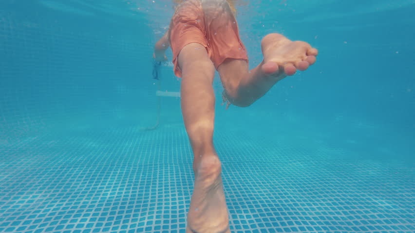 Happy little boy diving in pool blue clear water, fun for children. Summer swim, underwater leisure. Funny kid, enjoy diving. Extreme angle
