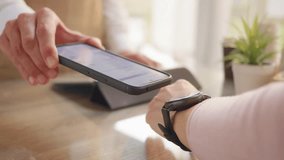 Contactless payment with smart watch and smartphone close up. Woman paying online at store counter, hand closeup. NFC electronic payment - Powered by Shutterstock - Get 15% off with code: PIKWIZARD15