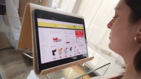 Woman using facial recognition on tablet screen for cashless transaction at store counter close up. Contactless payment and biometric ID verification closeup - Powered by Shutterstock - Get 15% off with code: PIKWIZARD15