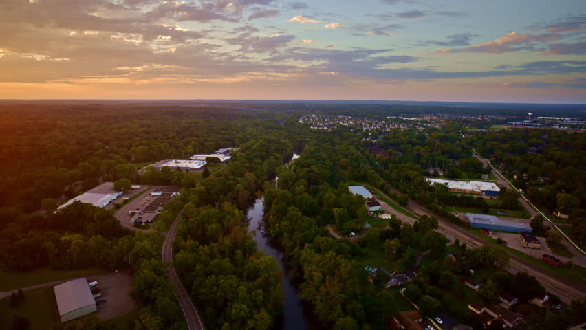 A drone travels above the Huron River on a sunny summer day, approaching Ypsilanti, Michigan.