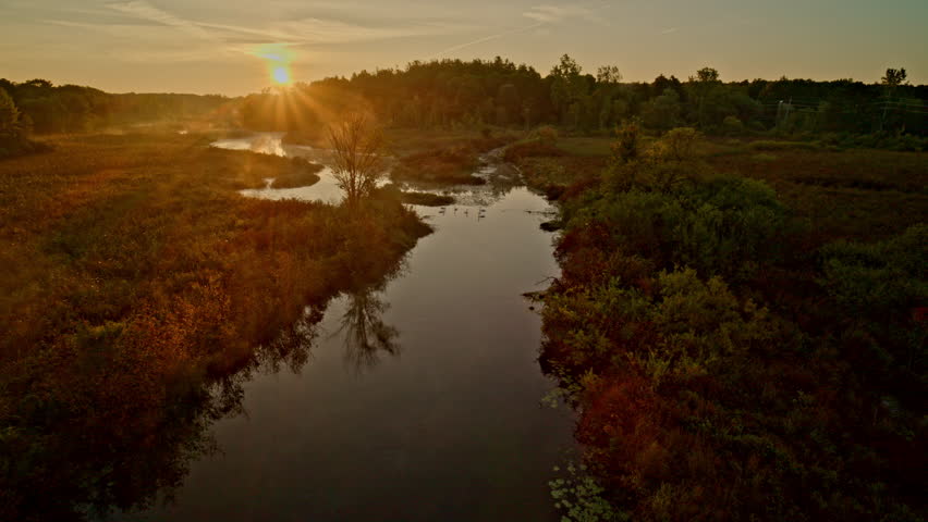A drone travels above the Huron River on a sunny summer day, approaching Milford, Michigan.