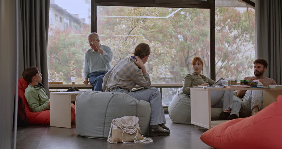 In a bright, modern library filled with natural light, students study and learn together, using bean bag chairs and tables to collaborate comfortably in an engaging educational environment.