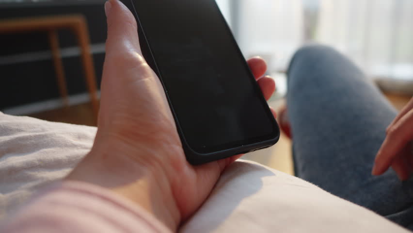 Woman confirming cryptocurrency payment on smartphone. Person hand clicking button on mobile screen while paying with crypto wallet online close up