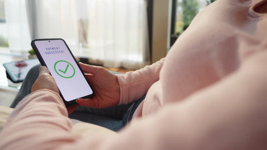Woman scanning finger print while approving payment on smartphone close up. Buyer paying online using biometric security technology and mobile phone