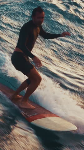 Man surfs the wave and does hand five trick by walking to the nose of the board. Aerial view of the male surfer riding the wave in the Maldives
