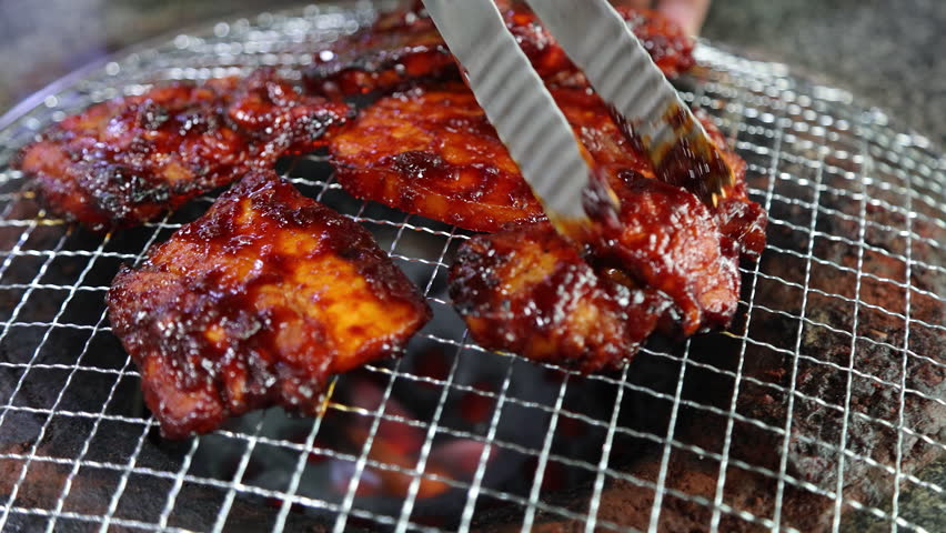 Meat sizzling on a grill over blazing charcoal