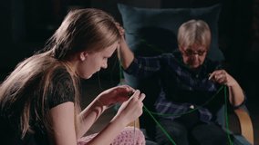 A teenage girl knitting with her grandmother near a glowing fireplace, sharing a cozy and heartwarming moment together - Powered by Shutterstock - Get 15% off with code: PIKWIZARD15