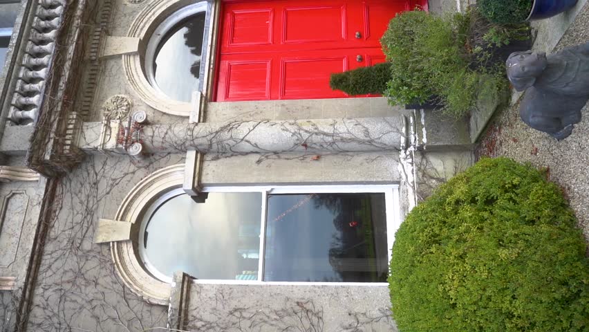 An Elegant Red Door Surrounded by Lush Greenery in a Beautiful Historic Building