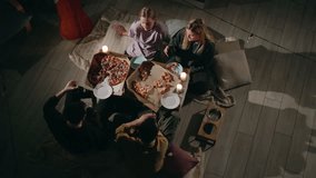 A group of young people eating pizza at a festive candlelit table with a bowl for their Golden Retriever being filled, enjoying a friendly family party, top view. High quality 4k footage - Powered by Shutterstock - Get 15% off with code: PIKWIZARD15