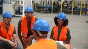 Multiracial team of engineers wearing safety vests and hardhats listening to their supervisor during a meeting in a robotics factory - Powered by Shutterstock - Get 15% off with code: PIKWIZARD15