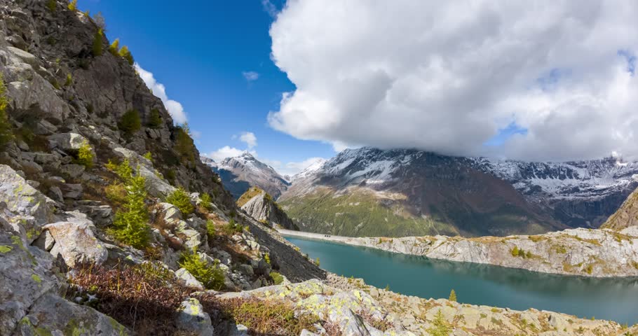 Stunning timelapse capturing the serene Lake Pirola surrounded by rugged alpine peaks, dynamic clouds, and vibrant autumn colors