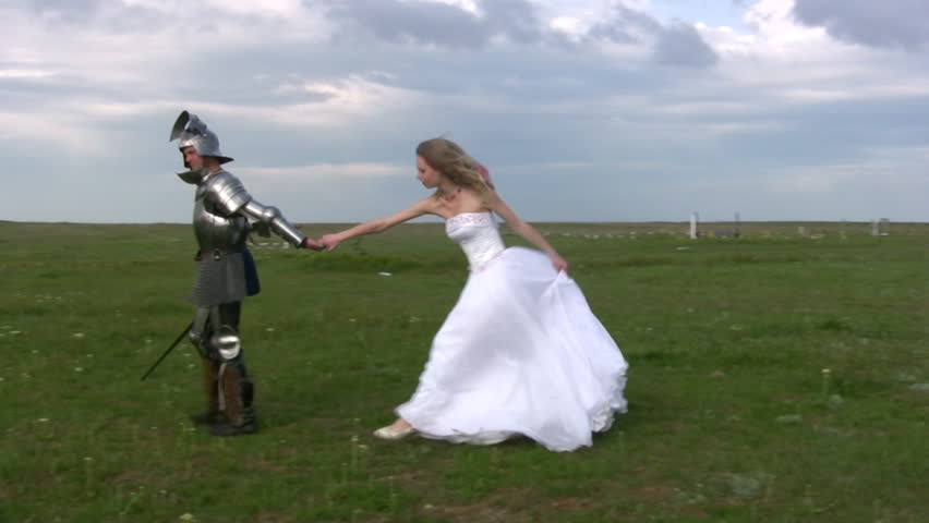 Man in medieval armor is excellent for  girl in a white wedding dress on the