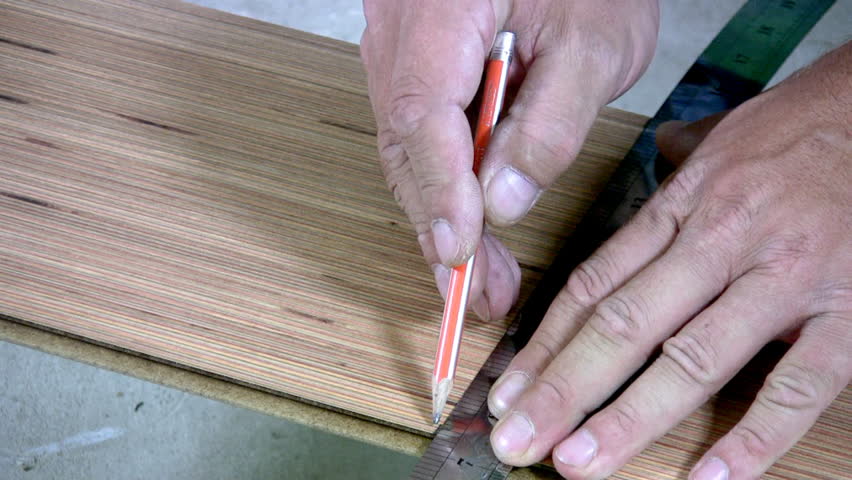 Men's hand draw a pencil line on the laminate. Men's hands are doing sawing with