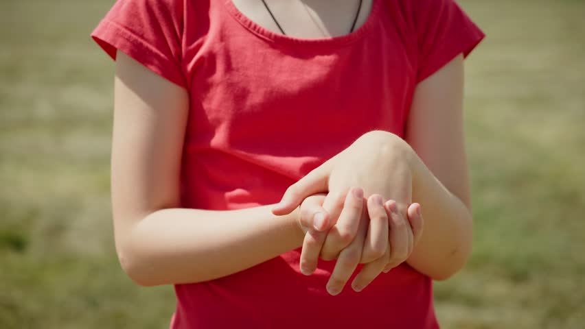 Unrecognizable girl warming up wrists and joints with rotational movements. Female stretching hands and joints, making circular motions. Girl loosening up wrists and joints, performing rotating
