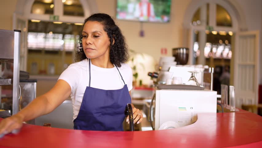 Employee cleaning counter at cafe. Latin small business owner preparing table at restaurant.